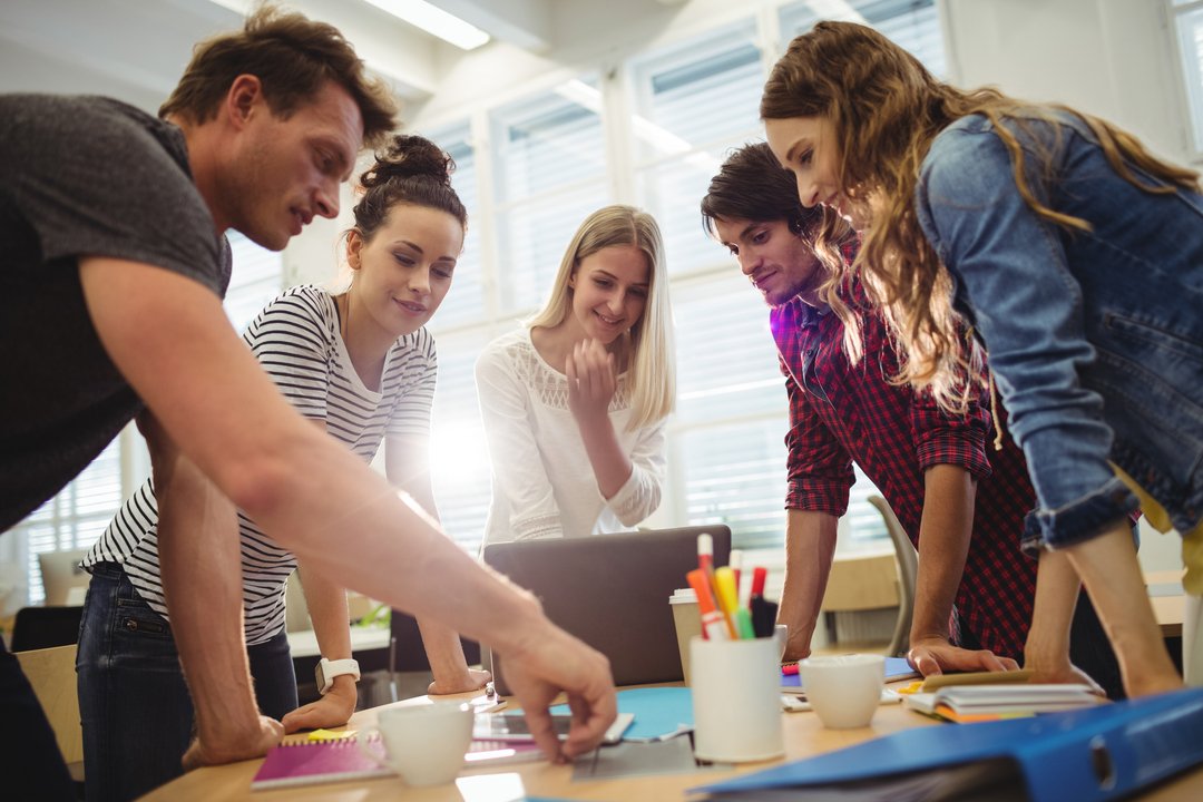 Grupo de pessoas no trabalho reunidas enquanto discutem como melhorar a comunicação interna.