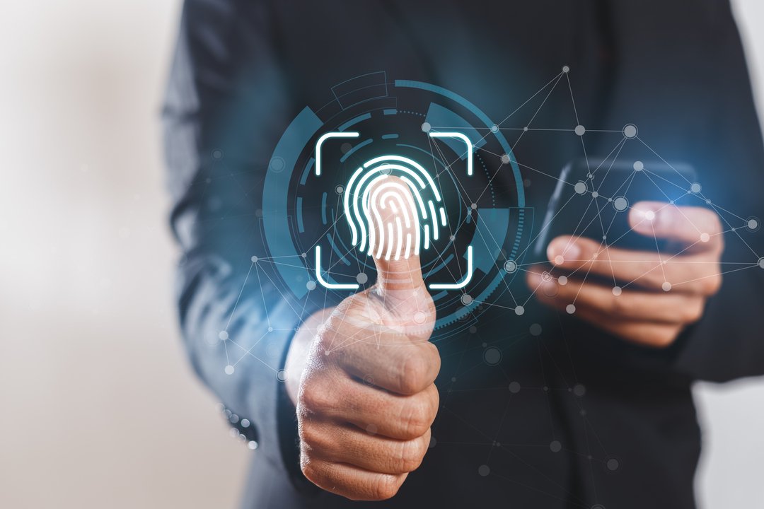 A foto mostra um homem de negócios utilizando o scanner digital na tela e usando o celular, fazendo o controle de ponto eletrônico.